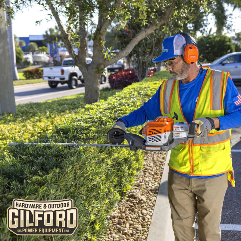 A professional landscaper using the STIHL HS 87 T hedge trimmer to shape hedges, highlighting its powerful performance and ease of use.