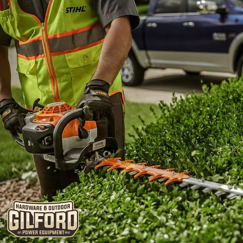 Professional landscaper using the STIHL HS 82 R hedge trimmer for precise hedge trimming in residential settings