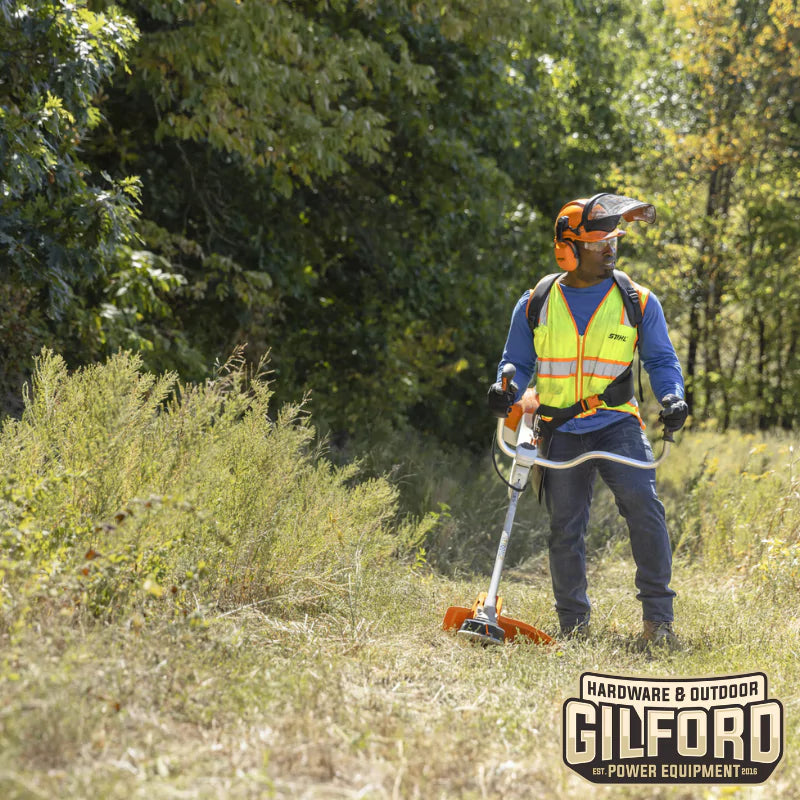 Professional landscaper operating the STIHL FS 361 C-EM gas-powered trimmer with Easy2Start™ system in dense vegetation.